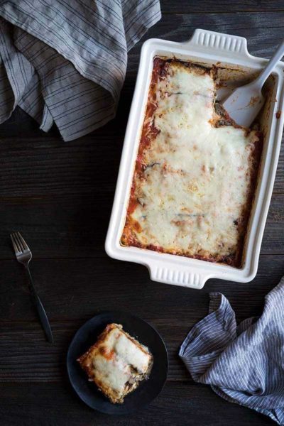 Eggplant lasagna recipe in a casserole dish with one slice on a plate