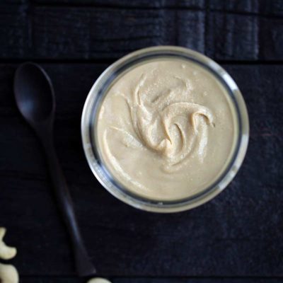 Homemade cashew butter in a jar next to cashews