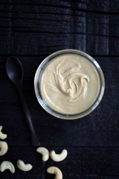 Homemade cashew butter in a jar next to cashews