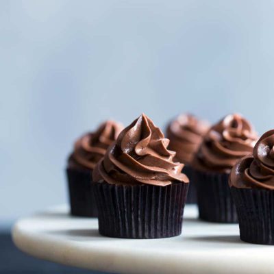 plated chocolate cupcakes topped with swirls of fluffy chocolate buttercream frosting