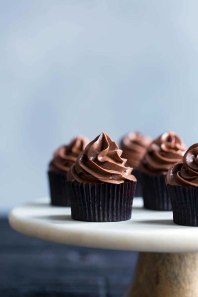 plated chocolate cupcakes topped with swirls of fluffy chocolate buttercream frosting
