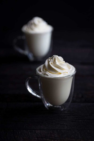 hot white chocolate in mugs topped with whipped cream