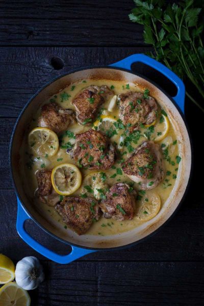 A photo of crispy baked chicken thighs in a blue casserole dish