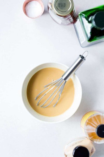 Ingredients for honey mustard vinaigrette surrounding a bowl with the finished dressing.