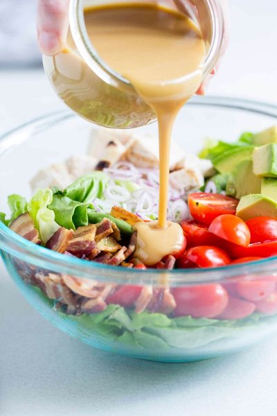 Honey Mustard Vinaigrette being poured over salad.