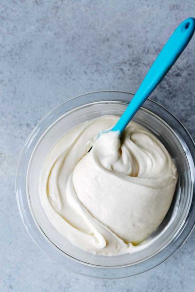 Cream cheese frosting recipe in a bowl with a blue spatula