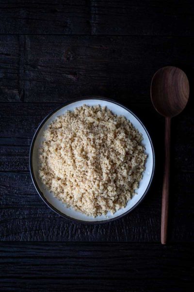 cooked quinoa in a large white bowl next to wooden serving spoon