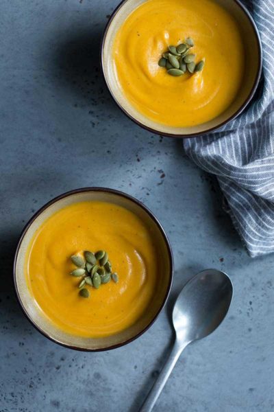 Sweet potato soup recipe served in two bowls, topped with roasted seeds