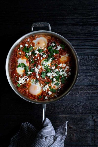Shakshuka recipe in a skillet with a towel around handle of pan