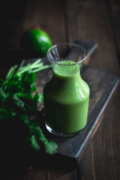 Cilantro Lime Dressing in a glass bottle on a cutting board