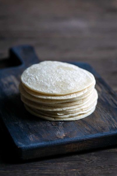 stack of homemade corn tortillas on a cutting board