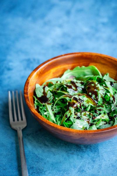 Balsamic reduction recipe drizzled over arugula with fork