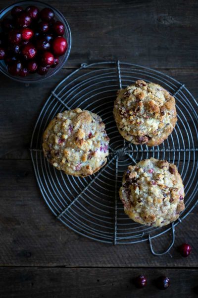 Overhead shot of three fresh cranberry muffins on a round cooling rack