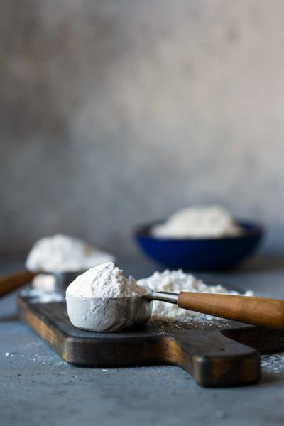 Different types of flour displayed in bowls and measuring cups
