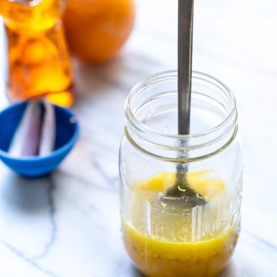 Honey orange vinaigrette recipe in a mason jar with a spoon