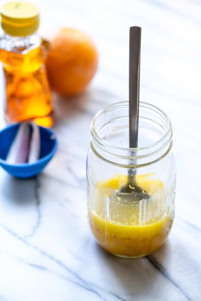 Honey orange vinaigrette recipe in a mason jar with a spoon