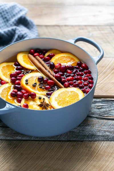 Stovetop potpourri ingredients in a Dutch oven, including orange slices and cinnamon sticks