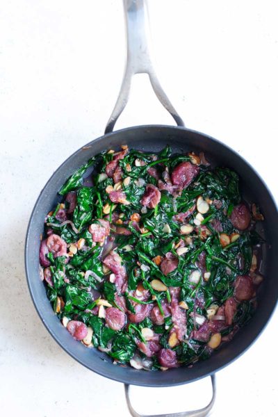 Sautéed spinach with grapes and almonds in a skillet shot from overhead