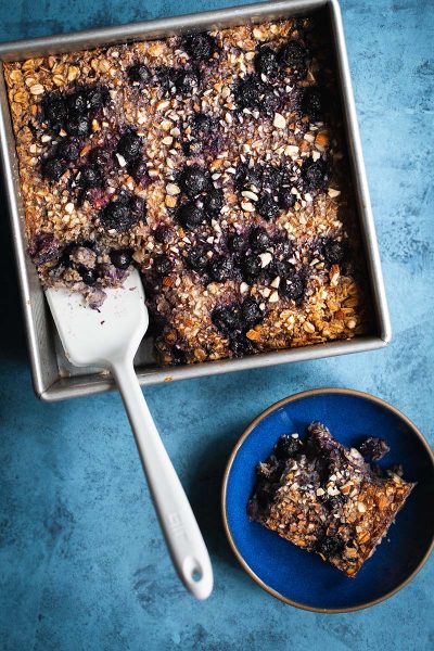 Baked oatmeal in am 8x8 pan with a spatula next to a single serving
